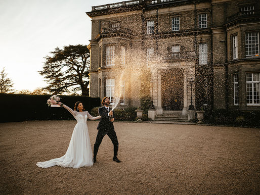 champange spray out side of hedsor house with bride and groom in the golden hour