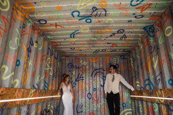 The bride and groom in a container playing crazy golf graffiti all over the walls