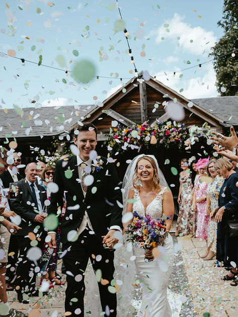 so much colorful confetti that fills the frame of the photos with bride and groom laughing at The stables at the ffolkes