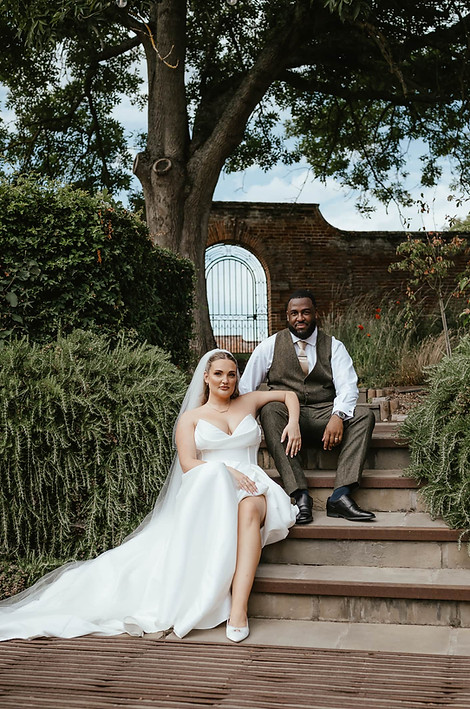 BRING AND GROOM SITTING ON THE STEPS AT WORSTEAD ESTATE BRIDE LEANING ON GROOMS KNEE