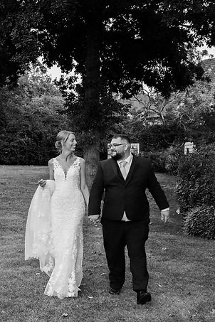 Bride and groom walking in a garden during wedding.