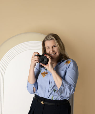 Female photographer smiling while holding a camera.