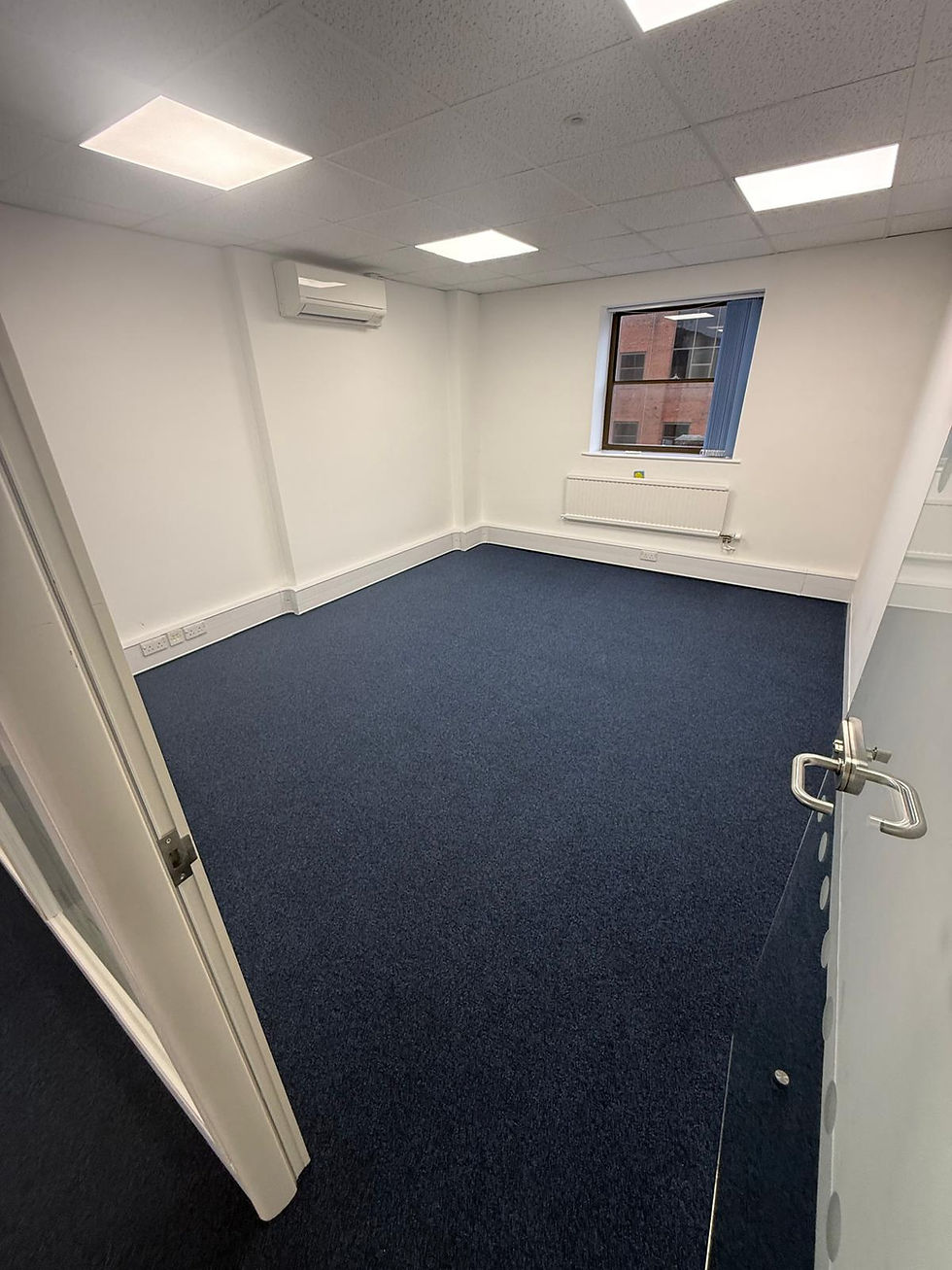 Empty office room with blue carpet and white walls.
