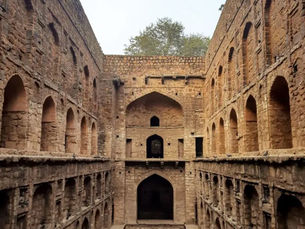 Historic masonry stepwell with multiple descending levels, where natural daylight gradually transitions into shadow, revealing depth, rhythm, and spatial hierarchy.