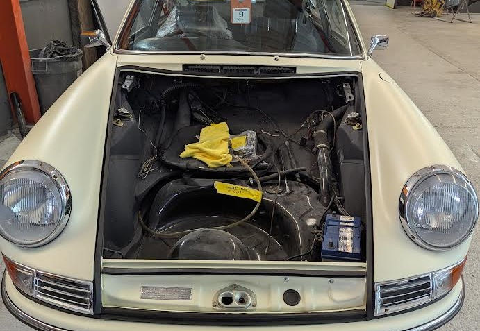 A rare 1967 Porsche 911 in a restoration workshop at Iver, undergoing windscreen replacement by My Car Glass LTD. The image highlights expert automotive glazing services for classic cars.