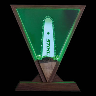 Epoxidharz-Lampe mit Mini-STIHL Kettensäge, beleuchtet im Holzrahmen.