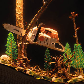 Epoxidharz-Lampe mit Mini-STIHL Kettensäge, beleuchtet im Holzrahmen.