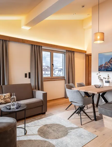 Gemütliches Wohnzimmer mit Sofa, Tisch und Bergpanorama im Hintergrund.