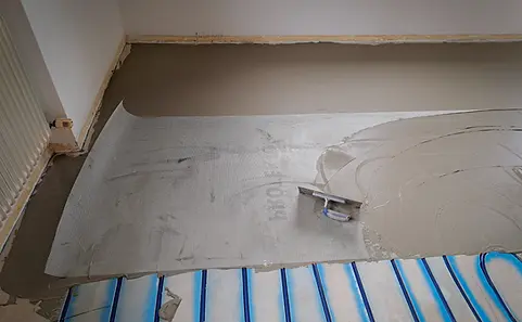 Verlegung des Bodens mit Fußbodenheizung, Spachtel, und Kleber in einem Raum.