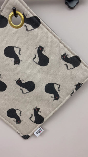Miniaturbild: Beiger Topflappen mit schwarzen Katzen und Messingöse
