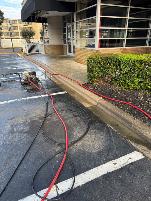 Pressure washer with red hoses on a wet parking lot