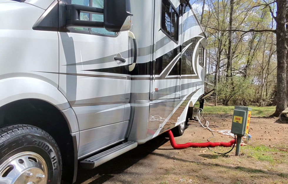 Clean silver RV with utility hookup at campsite
