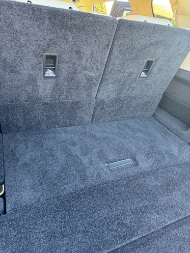 Grey car interior with carpeted floor and two rectangular openings in the back.