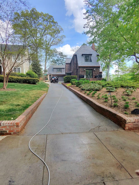 Pressure washing hose on a clean driveway leading to a house