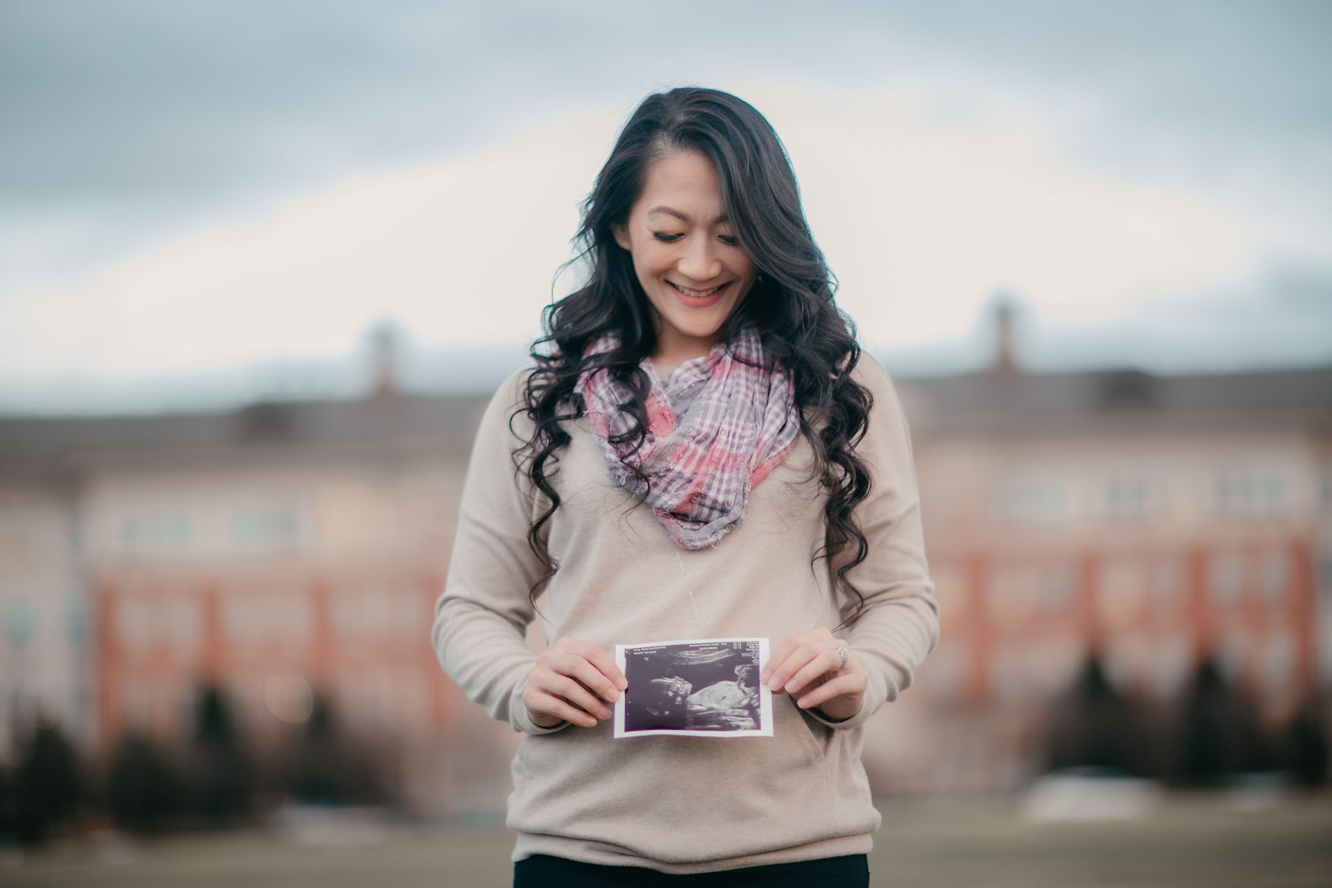 Pregnant announcement photo of mama holding a sonography photo