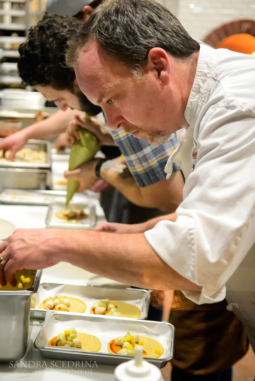 Teacher guiding a child through a practical life food preparation activity.