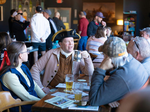 Historic reenactor dressed in late 18th century garb chats with 21st century patrons in a tavern