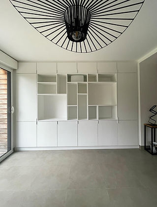 Aménagement sur mesure dans un séjour avec bibliothèque et rangements sur toute la largeur de la pièce, entièrement réalisé en blanc pour une lecture épurée.