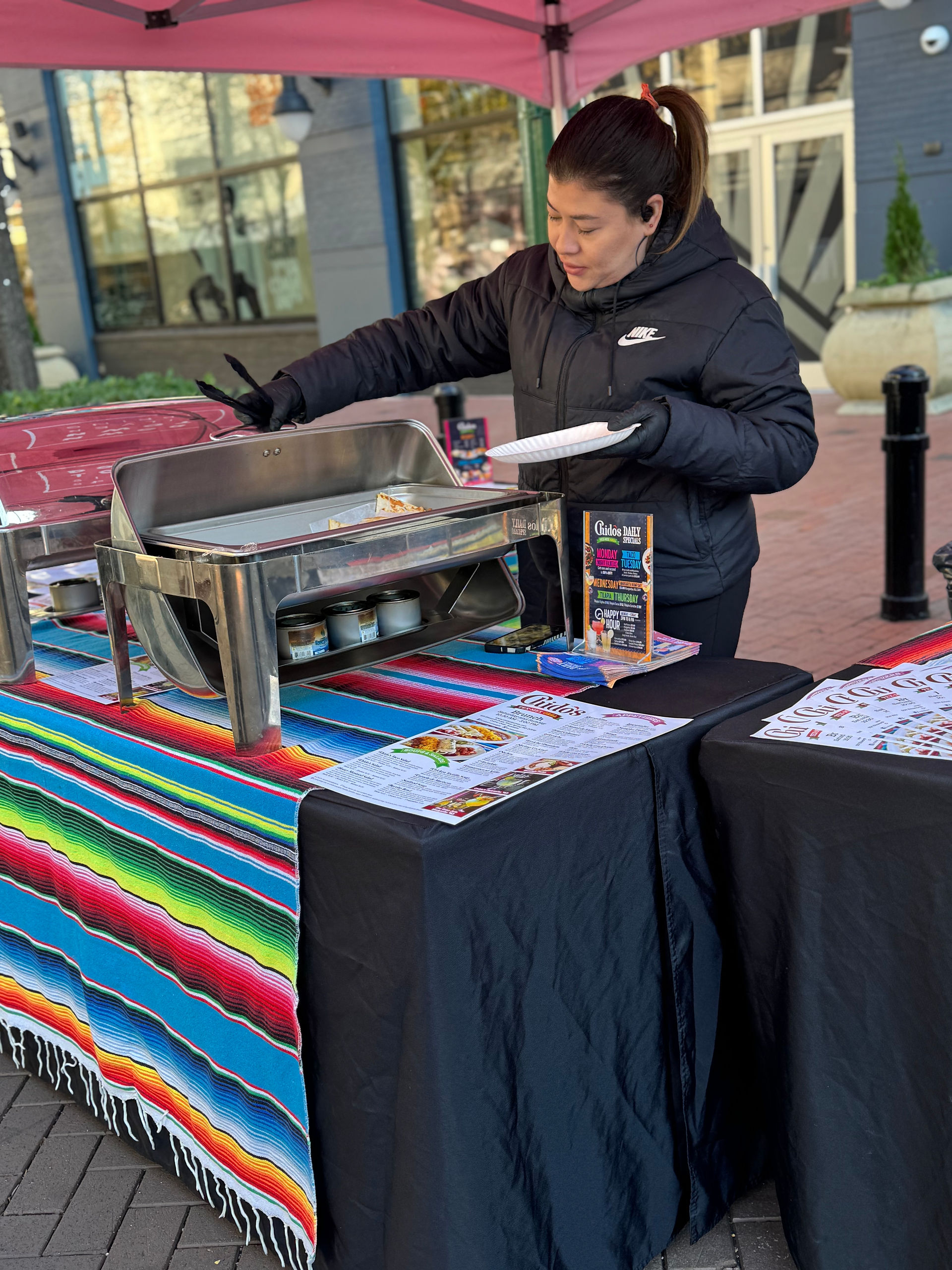 Vendor Displaying Handmade Crafts – A vendor showcases handmade items on a colorful tablecloth, engaging with attendees at the holiday market.