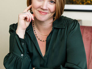 Headshot of Flagstaff Law Group founder Ashley DeBoard sitting at her desk looking at the camera wearing a dark green blouse