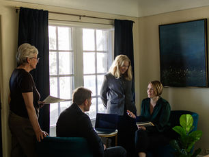 Attorney Ashley DeBoard meeting with two women and a man in a dark office - lighting is moody the tone is serious