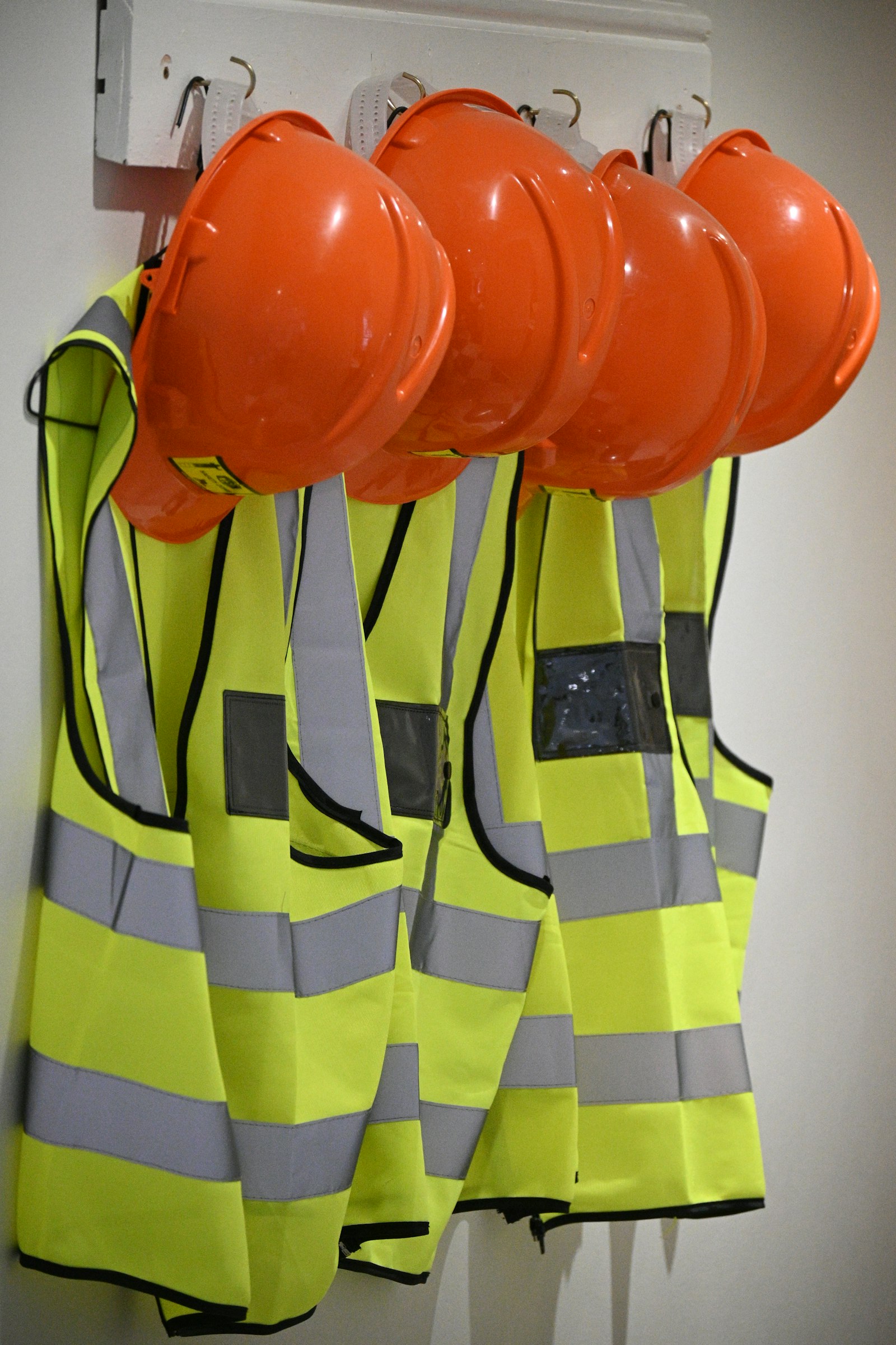 Hard hats and hi-vis vests hanging on a wall
