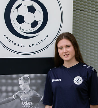 Lead Coach Lexie Kennedy standing next to ELEV8 Football Academy banner located at Bowral Football Club