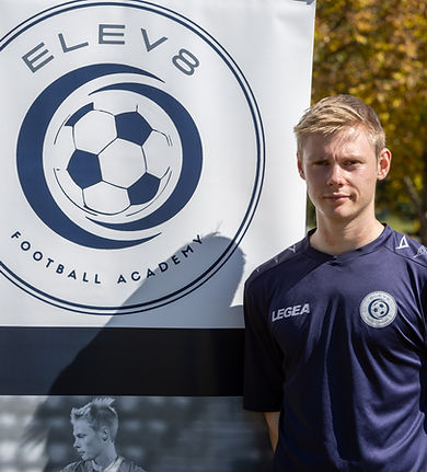 Head Coach Lochie standing next to ELEV8 Football Academy banner located at Bowral Football Club