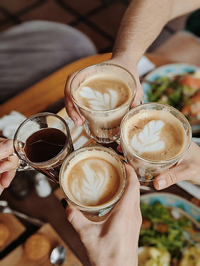 Four full coffee cups being held