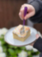 A slice of traditional British Old School Cake on a white plate as a fork cuts into the first bite.