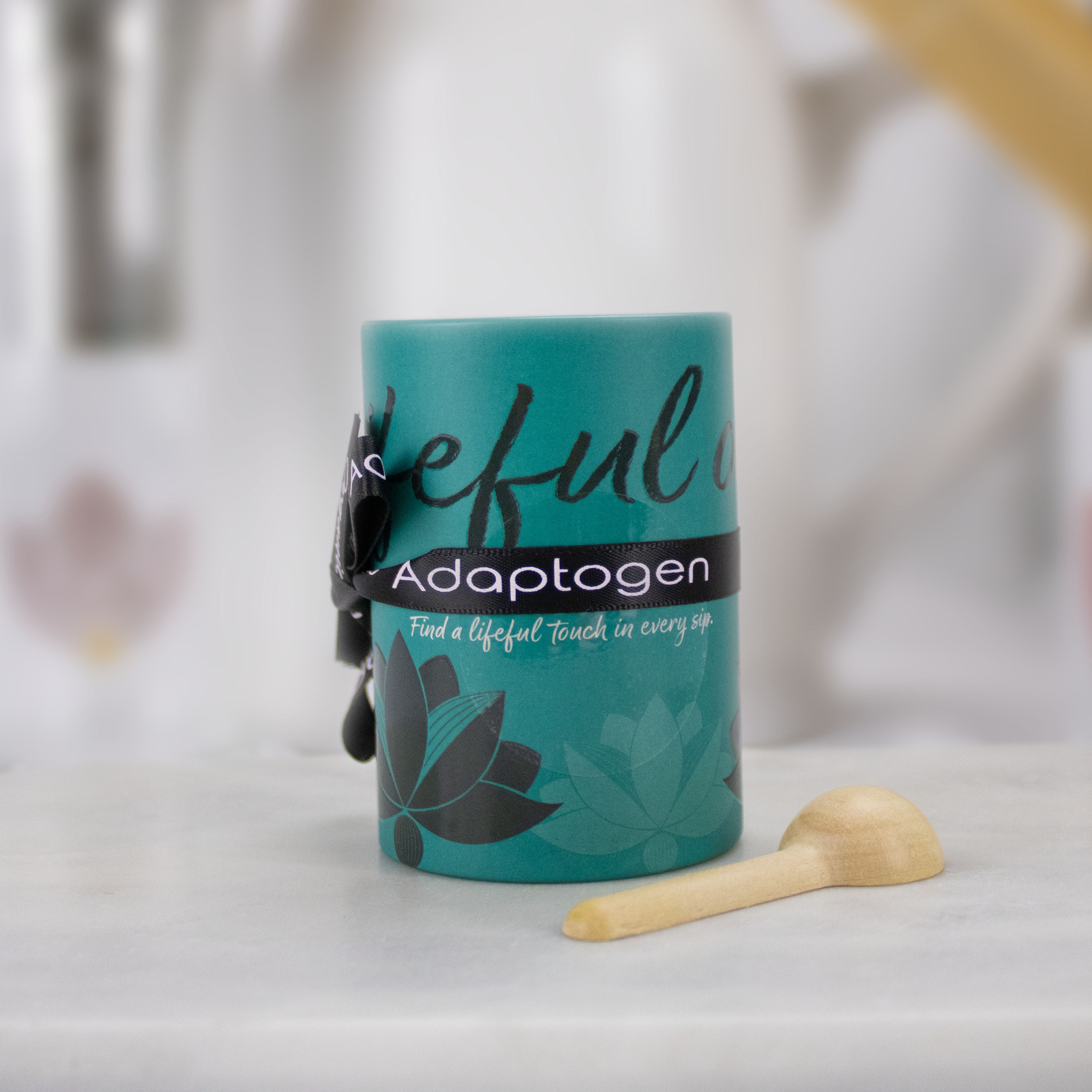 Teal Adaptogen Blend tea canister with scoop and ribbon on patterned background.