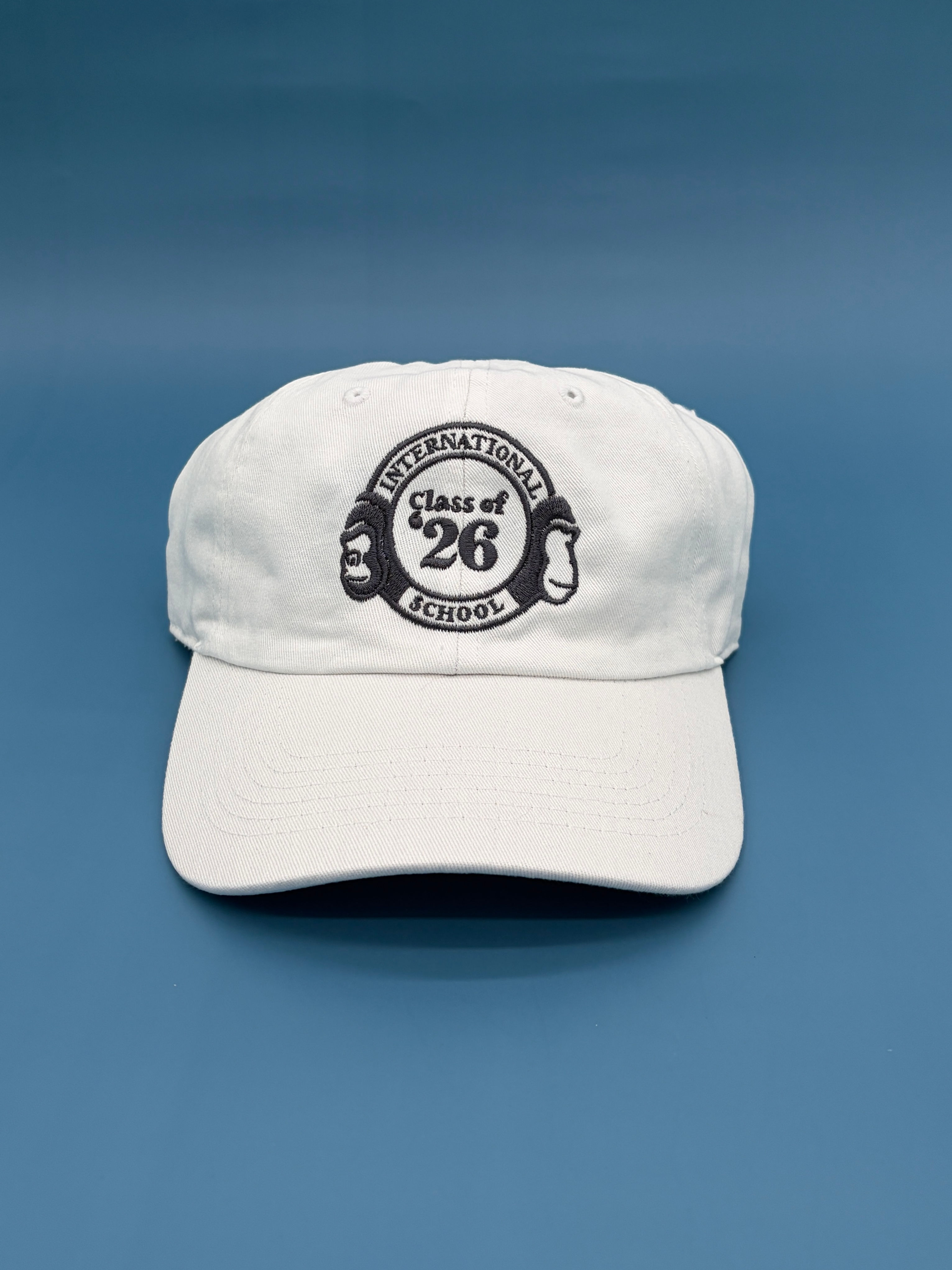 white dad cap with gray embroidery of international school insignia