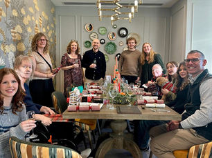 a group of people sat around a christmas Dinner table smiling