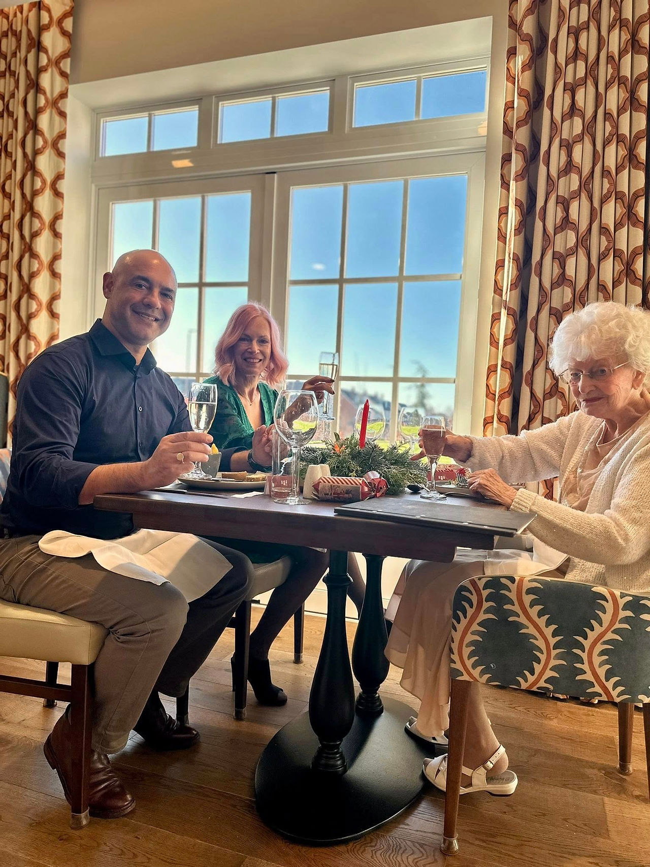 Two women and a man sat at a table having a christmas dinner together.