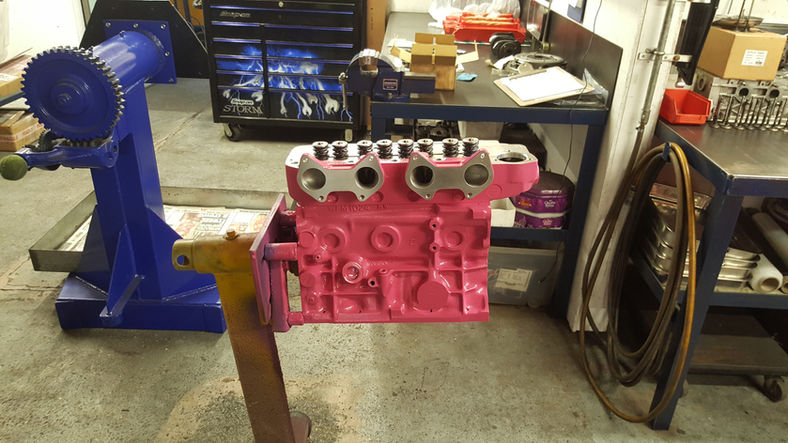 Pink engine block on a stand in a workshop