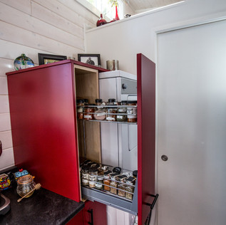 Cleverly designed pull-out spice cabinet beside stacked washer and dryer