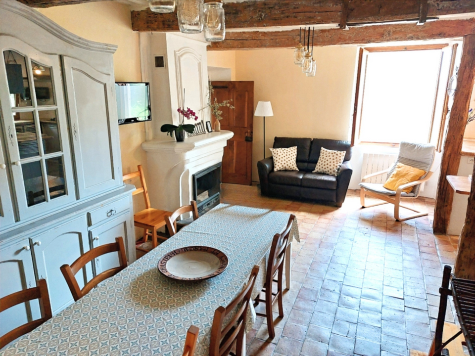 La salle de séjour avec grande table à manger et cheminée.
-----------
The living room with a sideboard, a large dining table, television, and a fireplace.