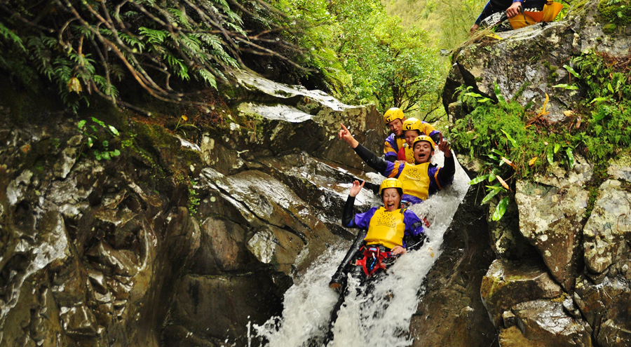 A beautiful natural rock slide and group having a wonderful time in Kaumira Canyon with Big Rock Adventures Canyoning