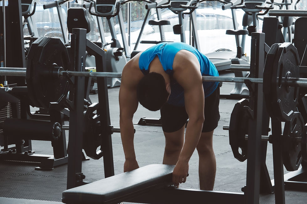 A man slumped over a barbell on a bench press station at a gym