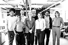The image portrays a group of joyful employees standing together. They exhibit a sense of belonging and connection to their workplace. Their expressions are positive, indicating happiness and satisfaction. The image captures a strong sense of camaraderie and teamwork among the employees, suggesting a healthy and inclusive work environment.