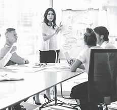 The image showcases a meeting room setting, with a female employee standing and actively explaining the strategy. She exudes confidence and enthusiasm, indicating a strong belief in a growth mindset. Her body language and gestures suggest effective communication and engagement with the audience. The meeting room appears professional and organized, providing a conducive environment for strategic discussions. The image captures the spirit of knowledge sharing, collaboration, and a forward-thinking approach within the workplace.