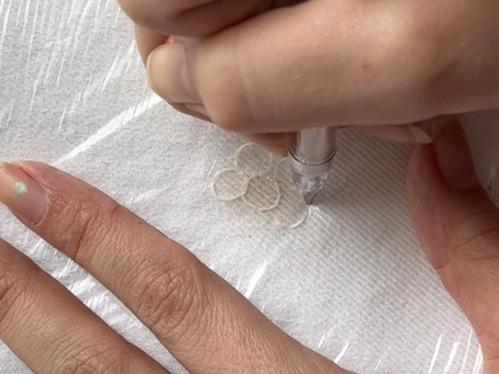 White denim fabric with stain, hands drawing a cover-up design