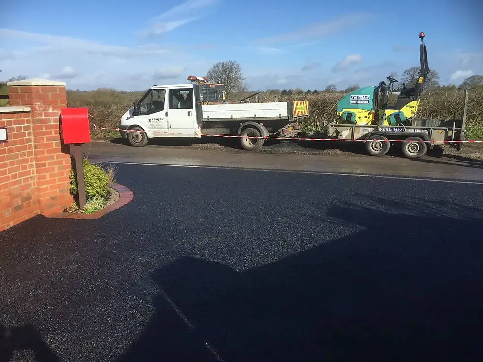 White work truck and mini excavator trailer parked near freshly paved tarmac driveway UK