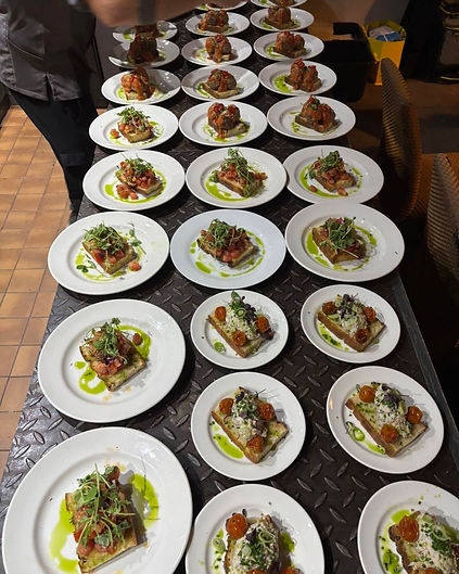 Multiple plates of gourmet starter dishes prepared on a kitchen counter