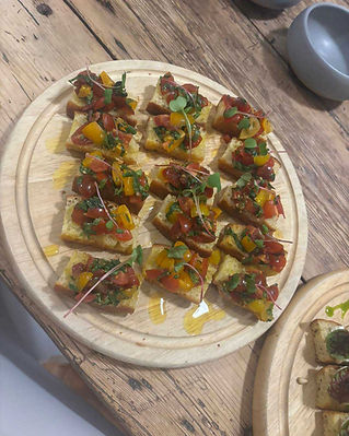 Round plate of seared meat crostini appetizers garnished with fresh herbs