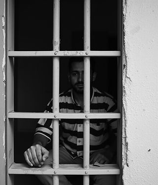 prisoner sitting behind bars .jpg