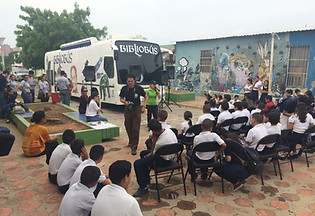 Actividad comunitaria con jóvenes reunidos al aire libre frente a un bibliobús, usada para ilustrar eventos educativos y prog