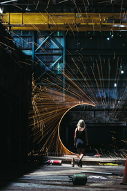 Woman walking into abandoned hangar with spark portal