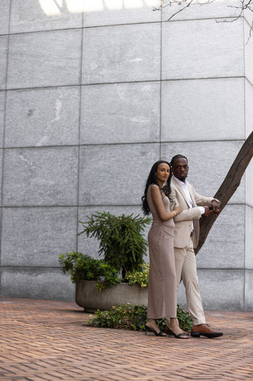 Neutral toned dressed couple poses for photographer in front of minimalistic Portland arch
