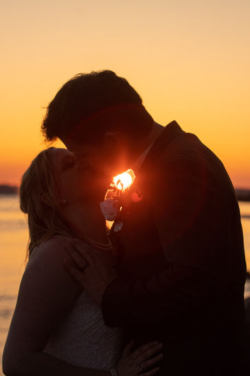 Bride and groom silhouette kiss at sunset